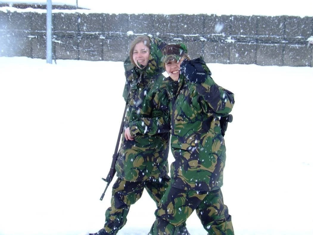 Duas pessoas em uniforme militar numa paisagem coberta de neve